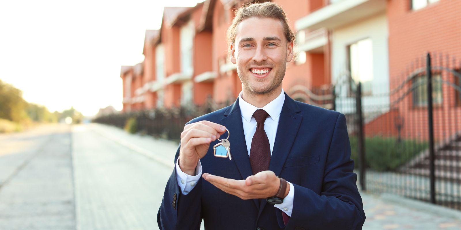 A real estate agent showing key on front of the houses